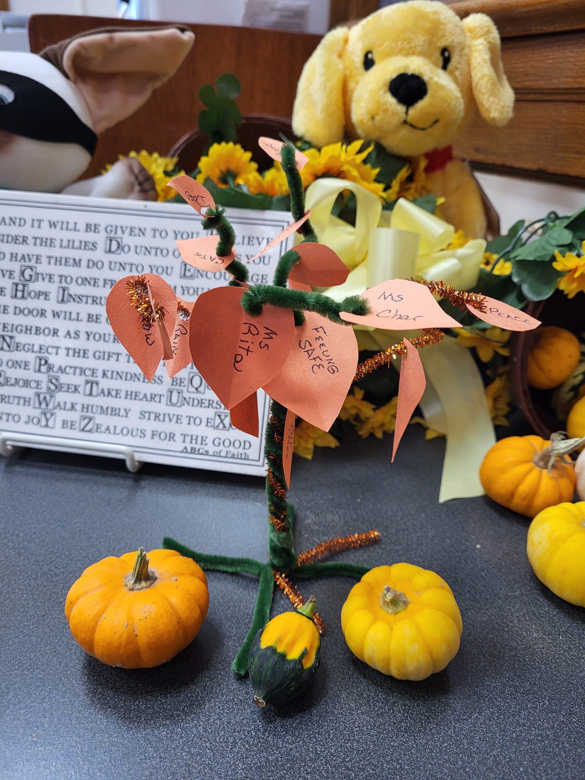 A photo of a "thankful tree" made of pipe cleaners and paper. Things/people that the person is thankful for are written on the paper leaves.